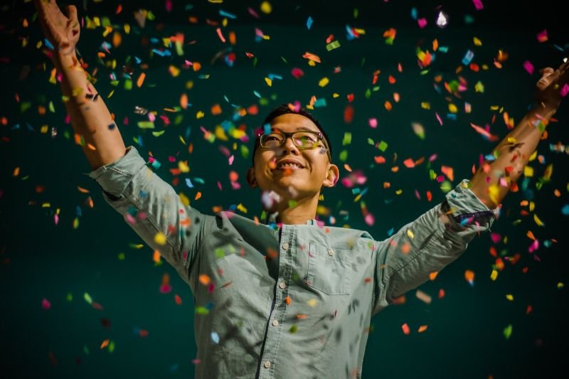 A person celebrating small writing victories with a smile and a raised fist, illustrating the power of positive reinforcement in overcoming writer's block